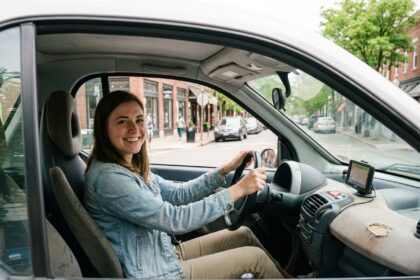 Jeune femme souriante dans une voiture en ville